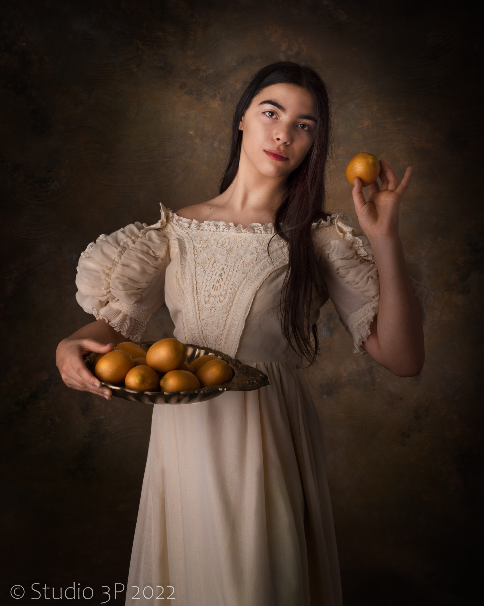 Elegant woman poses with pears in white cream dress